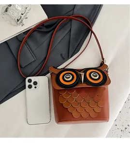 Macro view of brown owl bucket bag showing layered leather feathers and phone size guide