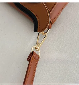 Detailed close-up of premium gold hardware hook and stitching on brown leather bag