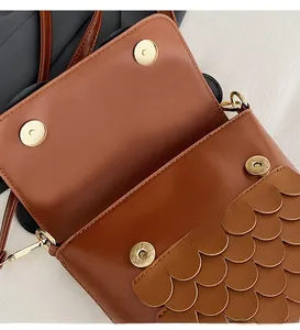 Macro detail of the brown owl bag featuring dual gold magnetic buckles and layered scales