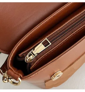 Detail of the owl shoulder bag showing gold metal zipper and magnetic buckle closure