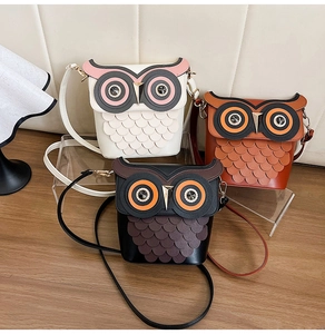 Detailed view of owl-shaped bucket bags in black, white, and brown with rhinestone eyes