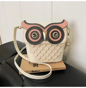 Close-up of cute owl bucket bag showing layered leather feathers and sparkling rhinestone eyes