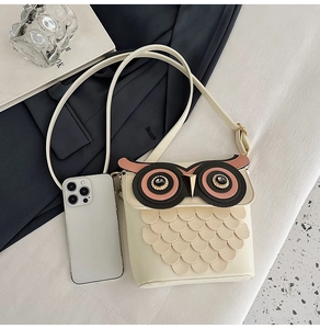 Detailed size comparison of owl-shaped crossbody bag next to a smartphone