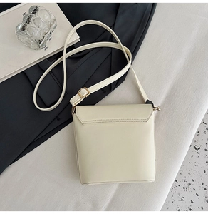 Top view of cream minimalist crossbody bag with adjustable gold buckle and fine stitching