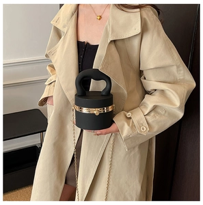 Detail of black cylindrical acrylic bag with gold chain strap and spherical lock