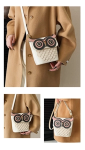 Detail of cute owl bucket bag featuring layered leather feathers and a white shoulder strap