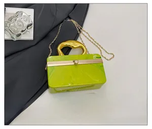 Dettaglio pochette in acrilico marmo verde con manico dorato rispetto a uno smartphone