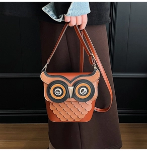Close-up of owl-shaped bucket bag with layered feather textures and adjustable strap