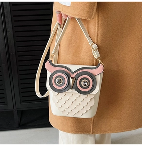 Detail of owl-shaped bucket bag featuring rhinestone eyes and feather scale design