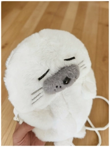 Detail view of white plush seal crossbody bag showing soft texture and sleepy face embroidery