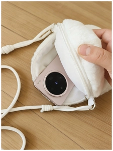 Close-up of white plush crossbody bag showing zipper opening and smartphone storage