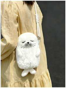 Detail of white plush seal crossbody bag with woven rope strap and metal hardware