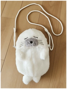 Detail showing the white plush seal bag material with embroidered face on wooden floor