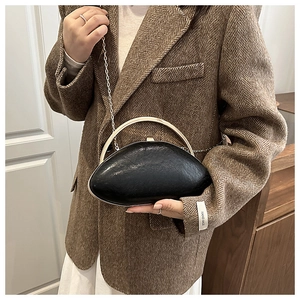 Black oval acrylic evening clutch with gold metal handle and chain strap on a model