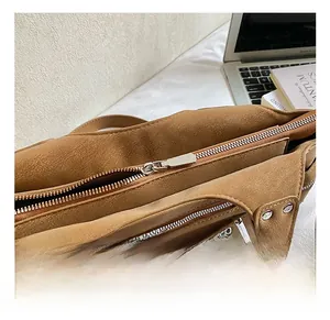 Detail view of the secure metal zipper and internal storage layers of the brown bucket bag