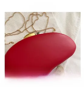 Detail of red matte evening clutch with gold and silver pebble-shaped metal clasp and chain