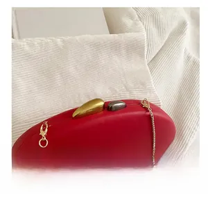 Detail of red oval acrylic evening bag featuring a gold pebble clasp and chain