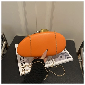 Close-up of pebble-shaped orange evening clutch with golden chain and metallic lock