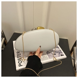 Detail of matte acrylic evening clutch bag featuring dual-tone pebble locks and gold chain