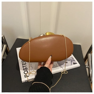 Macro detail of brown pebble-shaped acrylic clutch with geometric metal clasp