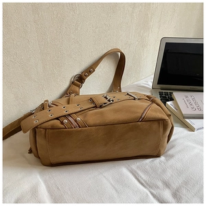 Detailed close-up of brown vintage biker tote bag with studs and decorative zippers