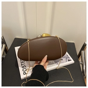 Detail of acrylic pebble clutch with two-tone metal clasp and gold chain strap
