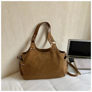 Close-up of vintage brown tote bag featuring silver rivet hardware and dual handle design