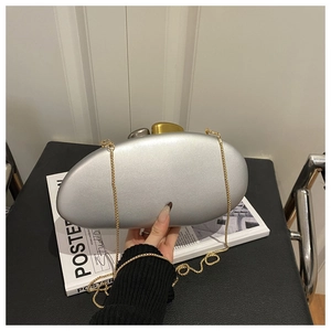 Detail view of silver pebble-shaped evening clutch with gold chain and metal clasp