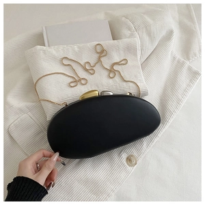Detail of black acrylic evening clutch with gold chain strap and pebble clasp
