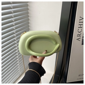 Detail of light green acrylic wrist bag with round handle and gold chain strap