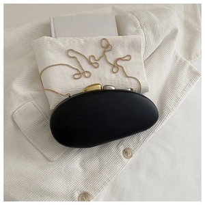 Detail of black oval acrylic bag with asymmetric gold and silver metal clasp and chain