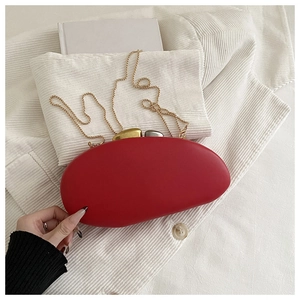 Macro shot of red oval evening bag featuring unique gold pebble-shaped metal clasp