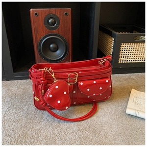 Détail du sac à bandoulière rouge à pois en similicuir brillant avec charme de cœur