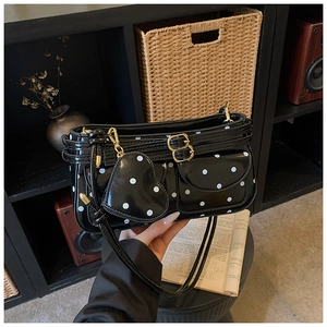 Détail du sac rétro noir à pois avec breloque coeur et accessoires dorés brillants