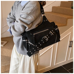 Detail of punk style black tote bag with silver eyelets, metal zippers and multi-pockets