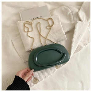 Detailed top view of a dark green clutch bag with a unique gold C-shaped metal handle