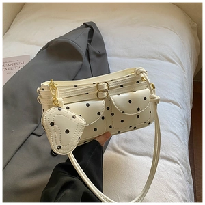 Détail du sac à bandoulière blanc à pois avec breloque cœur et boucles métalliques