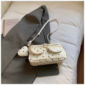 Détail du sac bandoulière blanc à pois avec poches à boucles et breloque cœur