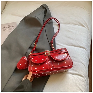 Détail du sac sous le bras à pois rouges avec finition brillante et boucles dorées