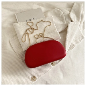 Top view of red cloud evening clutch bag with gold chain strap on white corduroy