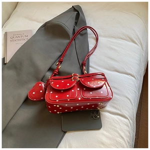 Détail d'un sac à main rouge à pois avec deux poches frontales et un pendentif en forme de cœur