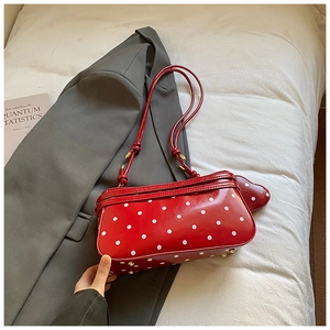 Détail du sac rouge à pois avec porte-monnaie en cœur posé sur un blazer gris