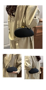 Detail of black oval hardshell evening bag featuring gold chain and pebble metal clasp