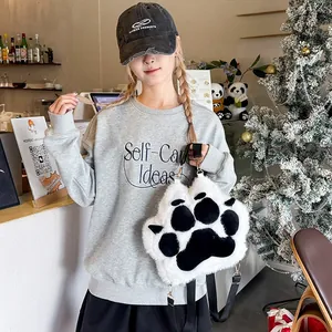 Detail of cute black and white plush cat paw backpack paired with a casual gray sweatshirt
