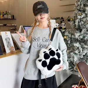 Close-up of a fluffy cat paw plush bag in black and white with an adjustable strap