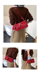 Détail du sac baguette à pois rouges avec breloque coeur et garnitures dorées sur l'épaule