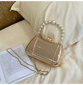 Details der goldenen Abendtasche mit Perlengriff und vertikaler Streifenstruktur