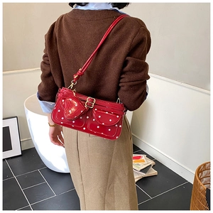 Détail du sac rouge à pois en cuir verni avec charm en forme de cœur et accessoires dorés
