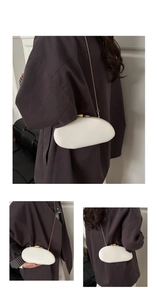 Detail view of white pebble-shaped evening bag with gold chain and matte finish
