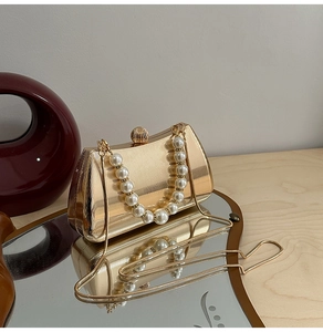 Detailaufnahme goldene Clutch mit Perlenhenkel und eleganter Schlangenkette